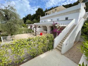 a white house with stairs and flowers at HMO Glamping & Suites in Vignanotica in Mattinata