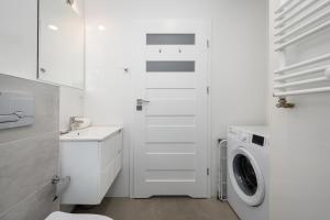 a white bathroom with a washing machine in it at Apartment Kamienna Krzyki with FREE GARAGE Wrocław by Renters in Wrocław