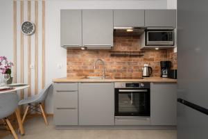 a kitchen with white appliances and a brick wall at Apartment Kamienna Krzyki with FREE GARAGE Wrocław by Renters in Wrocław