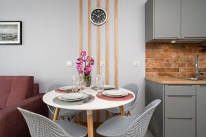 a dining room table with chairs and a clock on the wall at Apartment Kamienna Krzyki with FREE GARAGE Wrocław by Renters in Wrocław