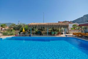 a large blue swimming pool with a thatch roof at Casablanca Hotel in Dalyan