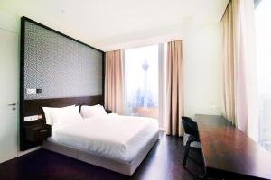 a bedroom with a bed and a desk and a large window at Tropicana The Residences KLCC By Luxury Suites in Kuala Lumpur