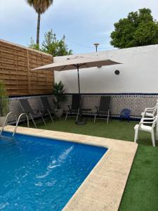 uma piscina com um guarda-sol e cadeiras e uma mesa e um guarda-sol em casa grande en Córdoba, pueblo de la Victoria , 6 dormitorios em La Victoria