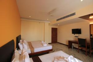 a hotel room with two beds and a television at Pondy Southern Residency in Puducherry