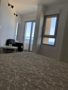 a bedroom with a bed and a couch and windows at Alojamiento Torrevieja playa frente al mar in Torrevieja