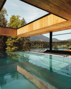 a house with a swimming pool with a wooden roof at Alpenhotel Kitzbühel am Schwarzsee - 4 Sterne Superior in Kitzbühel