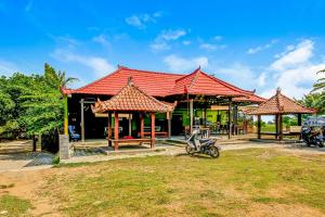 a building with a red roof with a motorcycle parked in front at OYO 91053 Desa Wisata Gilimanuk in Gilimanuk