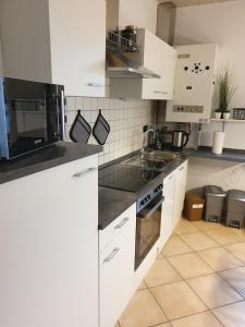 una cucina bianca con lavandino e forno a microonde di Haus Romy a Hagermarsch