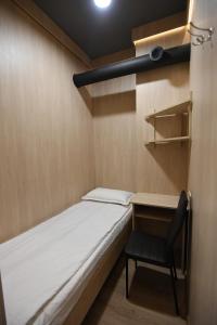a small room with a bed and a chair at CapsulePlus in Tbilisi City