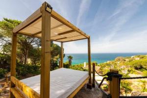 a wooden canopy bed with the ocean in the background at Villa El Buzo in Zahara de los Atunes