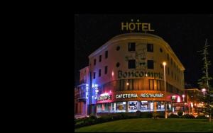 a hotel with a sign on the side of it at night at Hotel BONCOMPTE in Ponst