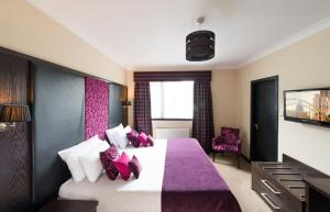 een slaapkamer met een groot bed met paarse en witte kussens bij The Popinjay Hotel in Larkhall