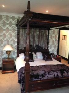 a bedroom with a canopy bed and a lamp at The Popinjay Hotel in Larkhall