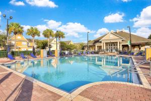 a large swimming pool with blue chairs and houses at Villas at Seven Dwarfs Resort - Near to Disney in Kissimmee