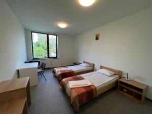 a hotel room with two beds and a desk and a window at UCU INN - Кімнати для гостей in Lviv