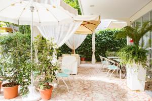 een patio met planten en stoelen en een parasol bij Hotel Ada in Rimini