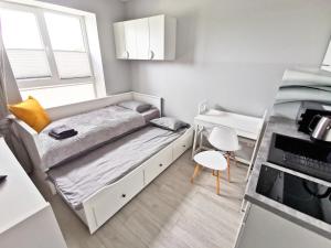 a small bedroom with a bed and a desk at Apartamenty Fińska Gdynia in Gdynia