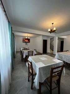 a dining room with tables and chairs and a chandelier at Cabana Mullerhaus in Tău Bistra