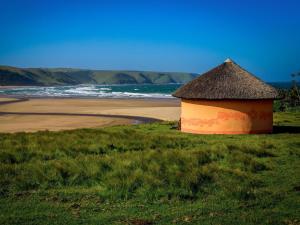 Bulungula Xhosa Community Lodge في Bulungulu: كوخ على الشاطئ بجوار شاطئ