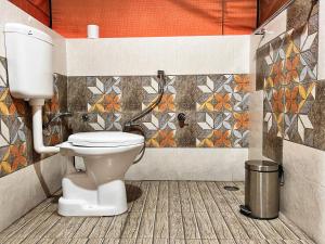 a bathroom with a toilet and a mosaic wall at North Deodar Camps in Kasol