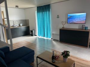 a living room with a blue couch and a tv at Zagajka SUN in Sarbinowo