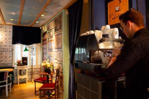 a man standing at a counter in a coffee shop at Rosalia's Menagerie Cocktail bar & InnUpstairs in Amsterdam