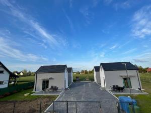 two white buildings with a blue sky in the background at Zagajka SUN in Sarbinowo