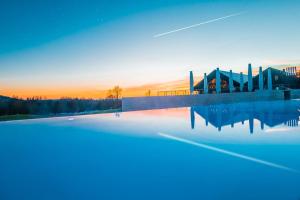 um reflexo de um edifício na água ao pôr do sol em Der Öschberghof Golf Resort des Jahres 2024 em Donaueschingen