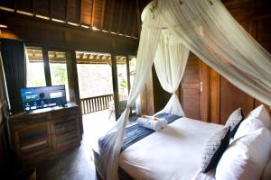 a bedroom with a canopy bed and a television at Sebatu Tulen Villa in Tegalalang