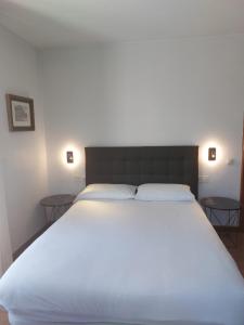 a bedroom with a large white bed with two tables at Hotel Cantabrico in Liérganes