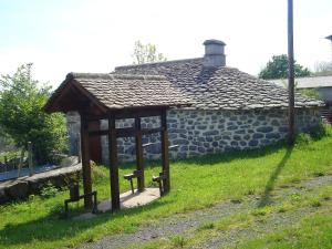 a wooden pavilion in front of a stone building at Maison de 4 chambres avec terrasse amenagee a Valuejols 