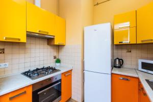 kuchnia z żółtymi szafkami i białą lodówką w obiekcie Avangard on Qn Romana St 26 Apart w Lwowie