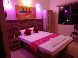 um quarto com uma cama grande e iluminação rosa em Utsav Grand by ShriGo Hotels em Pūrnia