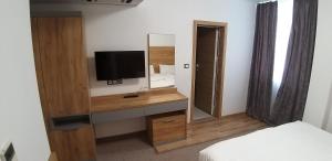 a bedroom with a television on a dresser with a mirror at хотел ВИЗИЯ in Haskovo