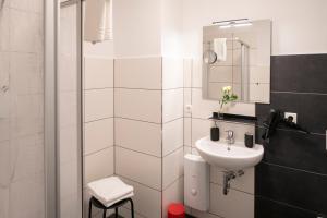a white bathroom with a sink and a shower at Weberhof Ferienapartments in Rostrup am Westufer des Zwischenahner Meers in Bad Zwischenahn