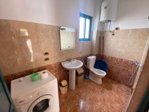 a bathroom with a toilet and a sink and a washing machine at DRINI in Velipojë