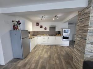 a large kitchen with white appliances and wooden floors at Loft du sud ouest av garage in Laplume