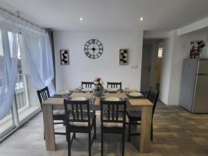 a dining room with a table and chairs and a clock at Loft du sud ouest av garage in Laplume