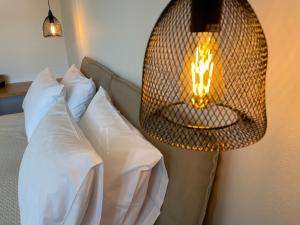 lámpara de mimbre colgada sobre una cama con almohadas blancas en Golden Evelyn, en Agia Paraskevi
