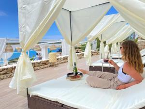 a woman sitting on a balcony overlooking a beach at Beach Club Menorca in Son Parc