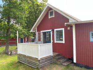 uma casa vermelha com um alpendre branco e uma varanda branca em Aspan Kurs & Lägergård em Ronneby