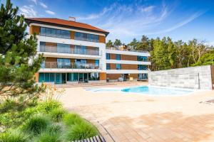 an exterior view of a building with a swimming pool at Baltica Heaven by 2HomeRent - przestronne apartamenty premium przy samej plaży in Rogowo