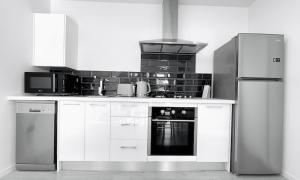 a kitchen with white cabinets and a stove and refrigerator at Ohope Villas with Spa,Sauna,Pool, Adults Only in Ohope Beach