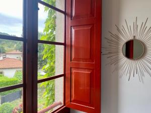 a window with a red door and a mirror at El Balcón del Eume, Cantina Río Covés in Puentedeume