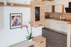 a kitchen with white cabinets and a vase with flowers at Ferien im Lossatal in Großzschepa