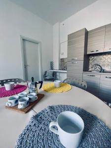 una cocina con una mesa con tazas y platillos. en Casa Vacanze , Scoglitti en Scoglitti