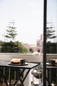 une table avec une assiette de nourriture et des tasses sur un balcon dans l'établissement GreyHouse Corfu διαμέρισμα στο κέντρο τις Κέρκυρας, à Ágios Rókkos
