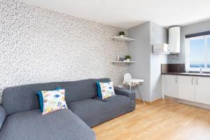 a living room with a gray couch and a kitchen at Home2Book Sea Views Caletillas in Candelaria