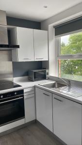 cocina con armarios blancos, fregadero y ventana en CityGo Apartments Queens Wellington en Belfast