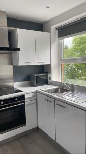 a kitchen with white cabinets and a sink and a window at CityGo Apartments Queens Wellington in Belfast +12 photos